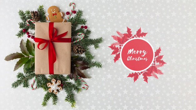 Free Christmas Composition With Green Leaves And Gift Top View Psd