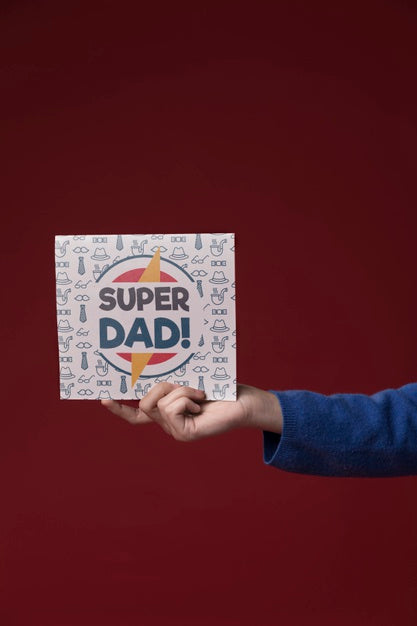 Free Hand Holding Cardboard Mock-Up On Burgundy Background Psd