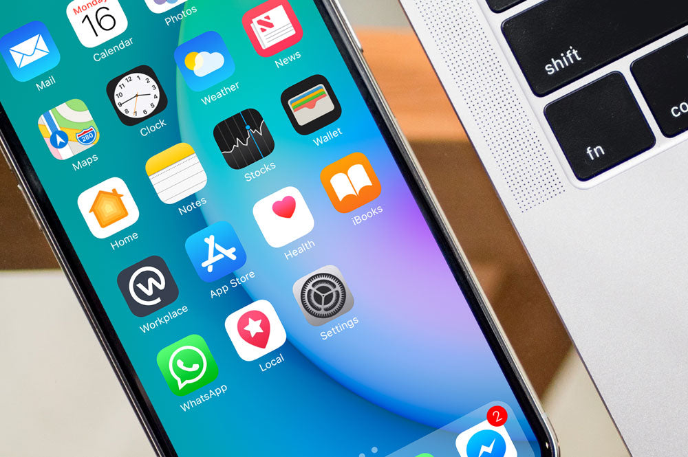 Free Black iPhone X on Glass Table with Macbook Pro PSD Mockup