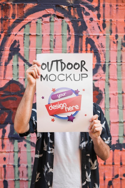 Free Man Presenting Poster Mockup In Front Of Graffiti Wall Psd