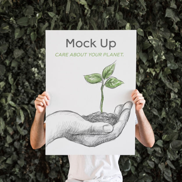 Free Man Presenting Poster Mockup In Front Of Leaves Psd