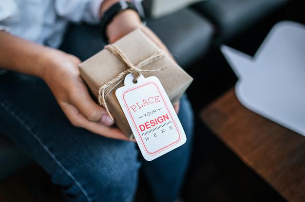 Free Woman'S Hand Hold Gift Box With Price Tag Psd Mockup Psd