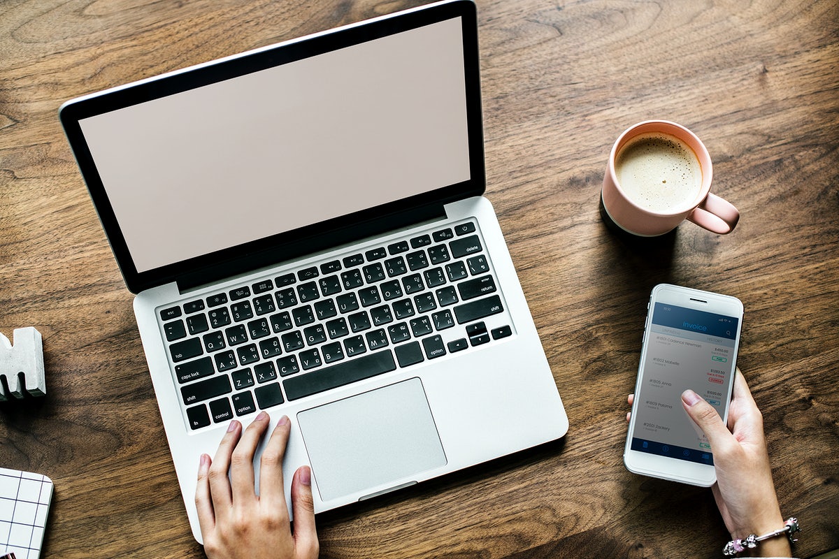 Free Aerial View Of Woman Using Computer Laptop And A Smartphone On Wooden Table