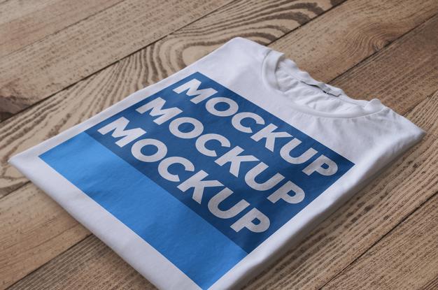 Free Folded White T-Shirt Over Wood Surface Mockup Psd