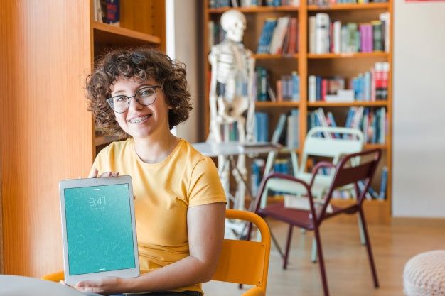 Free Friendly Woman Holding Tablet Mockup In Library Psd