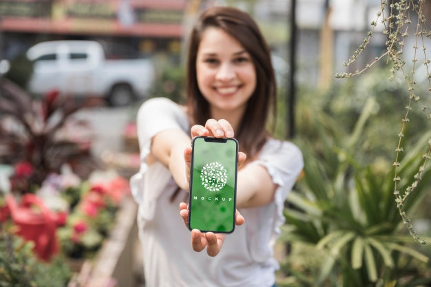 Free Girl Holding Smartphone Mockup With Gardening Concept Psd