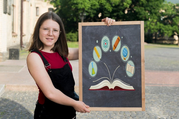 Free Girl With Glasses Holding A Blackboard Next To Her Psd