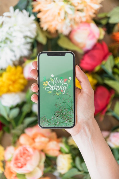 Free Hand Holding Smartphone Mockup Above Flowers Psd