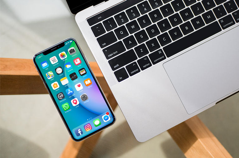 Free Black iPhone X on Glass Table with Macbook Pro PSD Mockup