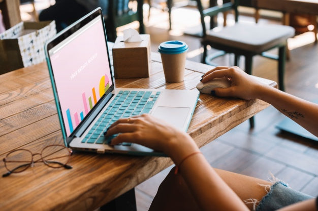 Free Laptop Mockup With Woman On Wooden Table Psd