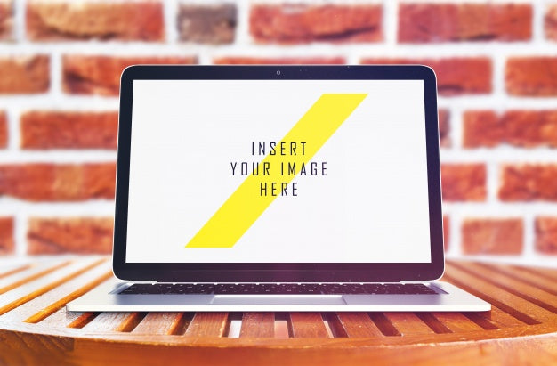 Free Laptop On Wooden Table In Front Of Brick Wall Mock Up Psd