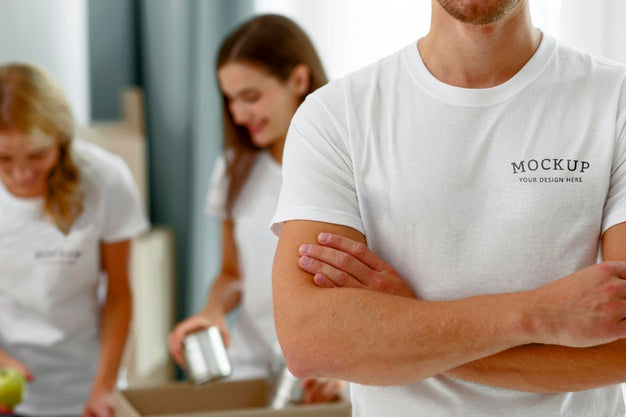 Free Male Volunteer Posing With Arms Crossed While Colleagues Prepare Donation Boxes With Food Psd