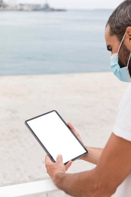 Free Man With Mask On Street With Tablet Reading Online Psd