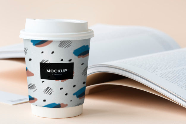 Free Takeaway Coffee Cup Mockup On A Table With An Open Book Psd