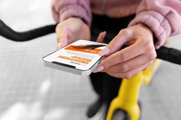 Free Woman Using Mock-Up Smartphone Outdoors While On Bicycle Psd