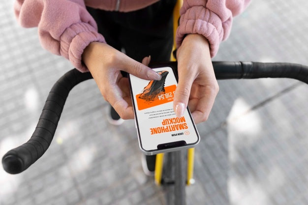 Free Woman Using Mock-Up Smartphone Outdoors While On Bicycle Psd